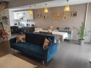 a living room with a blue couch and a kitchen at L'essentiel in Guemps