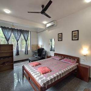 a bedroom with a bed and a chair in it at Studio Green Haven- R 7 by Mukund Sadan Arambol in Arambol