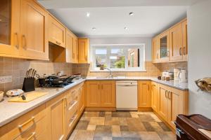 a kitchen with wooden cabinets and a white dishwasher at Spacious 6 Bed House in Waterlooville Portsmouth by Amber Stays, Perfect for Long Term Stays, Sleeps 14 in Waterlooville