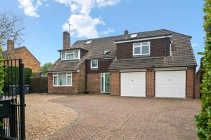 a brick house with two garage doors on a driveway at Spacious 6 Bed House in Waterlooville Portsmouth by Amber Stays, Perfect for Long Term Stays, Sleeps 14 in Waterlooville