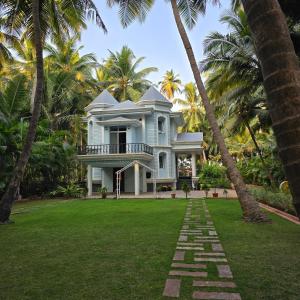 a house with palm trees in front of a yard at Sea Breeze, Guhagar in Guhagar