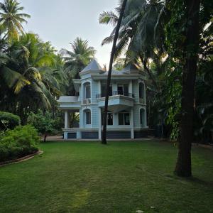 a large white house with palm trees in the yard at Sea Breeze, Guhagar in Guhagar