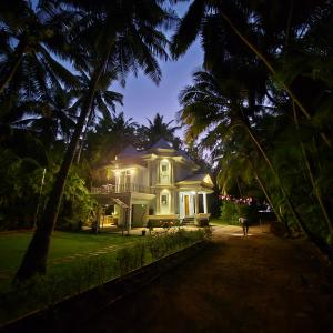a white house with palm trees in front of it at Sea Breeze, Guhagar in Guhagar