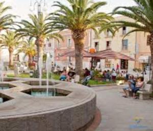 a fountain in a courtyard with palm trees and people at Gamm Simius Home Holiday in Villasimius
