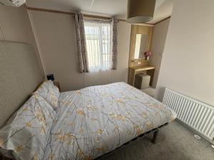 a bedroom with a bed with a quilt on it at Palm Grove 19 - Golden Palm - Central Heating, WiFi, pet friendly, bed linen - Meadow Lakes Caravan & Lodge Hire in Chapel Saint Leonards