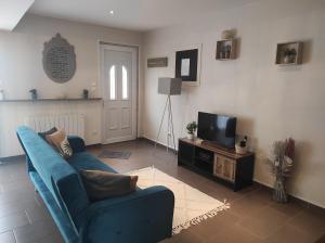 a living room with a blue couch and a television at L'essentiel in Guemps