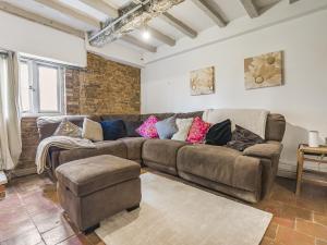 sala de estar con sofá marrón y pared de ladrillo en 6 Bedroom Country Cottage with Hot Tub, en Shifnal