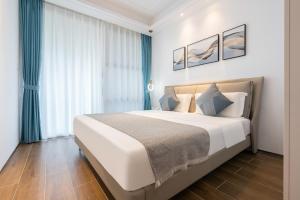 a bedroom with a large bed with blue curtains at 三亚海棠湾蔚蓝海湾公寓 in Sanya