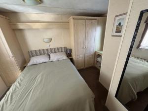 a small bedroom with a bed and a mirror at Hadrians Field 120 - Coastfields - WiFi, pet friendly, bed linen - Meadow Lakes Caravan & Lodge Hire in Ingoldmells