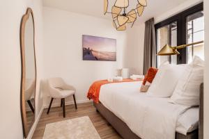 a bedroom with a bed and a chair and a mirror at Heritage Suites Antwerp in Antwerp