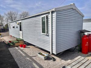 a white tiny house sitting on top of gravel at Swift 3-Bedroom Caravan Located in Uddingston, Glasgow at Maryville Caravan Site in Uddingston