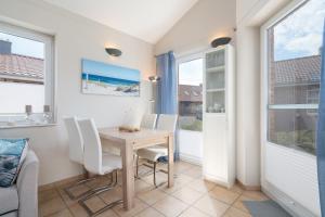 a dining room with a table and chairs and windows at Feriendorf Südstrand Haus 18 in Pelzerhaken +28 photos