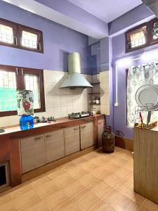 a large kitchen with purple walls and wooden floors at Townsville in Jorhāt +6 photos