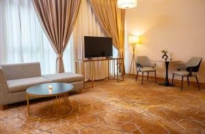 een woonkamer met een bank, stoelen en een tv bij La Zona Continental Hotel in Dubai