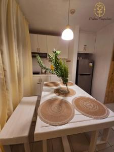a kitchen table with two plates and a plant on it at El Nissi Staycation, THE BARIQUIT SUITE, Enchanted Kingdom in Santa Rosa