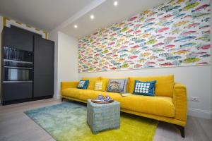 a living room with a yellow couch and a large painting at l'Isola di Vittoria in Porto Recanati