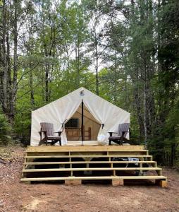 a tent with two chairs and a table in the woods at Gorgeous Safari Tent Rental Ideal for Glamping in Upstate New York in Wevertown
