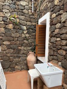 a bathroom with a sink and a stone wall at Dammuso Pensare alla Luna in Pantelleria +57 photos