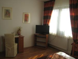 ein Wohnzimmer mit einem TV und einem Fenster in der Unterkunft Bliestal Hotel in Blieskastel