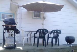 a grill and two chairs and a table with an umbrella at Holiday Cottage in Canora