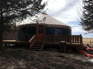 eine Jurte mit hölzerner Veranda und Treppe auf einem Feld in der Unterkunft Gorgeous Gibbon Yurt Ideal for Glamping in Nebraska in Kearney