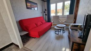 a living room with a red couch and a table at Gîte « Les Oyats » à 400 m de la plage in Équihen-Plage