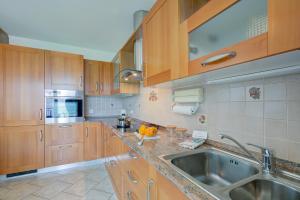 cocina con armarios de madera y fregadero de acero inoxidable en Casa Zaira 2 - Happy Rentals, en Caviano