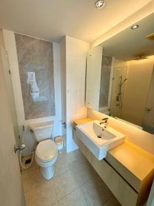 een badkamer met een wastafel, een toilet en een spiegel bij Better Homes at Atlantis Condo Resort in Jomtien Beach