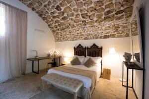 a bedroom with a large bed and a stone wall at Baglio Siciliamo Country House in Noto Marina +95 photos