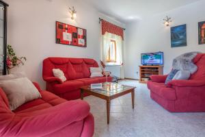 a living room with red couches and a tv at Villa Ornela, summer and sun, ideal for families and pets! in Santalezi