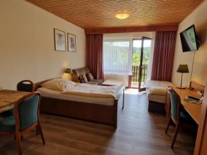 a hotel room with a bed and a table and chairs at Hotel & Apartmenthaus Zum Pfingsttor in Friedrichswald