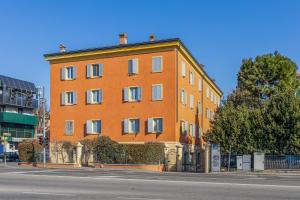 a large orange building on the side of a street at GuestHost - Cozy Flat X4 in a Historic Silk Mill in Modena