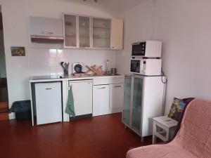 a small kitchen with white appliances and a couch at T2 La Treille avec extérieur non attenant in Allauch