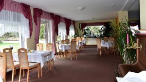 a dining room with tables and chairs and windows at Pension Schwesinger in Ottendorf-Okrilla