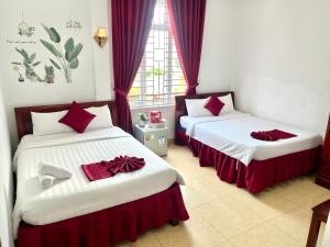 two beds in a room with red and white at OPA HOTEL HUE in Hue