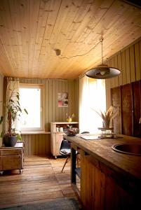 a kitchen with a wooden ceiling with a counter and a window at Pelēkā Māja, summer house for cosy stays in Myza Brenguli