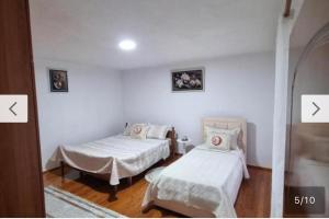 two beds in a room with two pictures on the wall at villa stavri in Pogradec