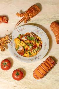 a plate of food on a table with tomatoes and seafood at Beach Walk Boutique Jumeirah in Dubai