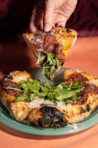 a person holding a slice of pizza on a plate at Beach Walk Boutique Jumeirah in Dubai