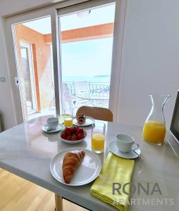 a table with a breakfast of croissants and orange juice at Rona Spacious apartment with a panoramic view in Ičići