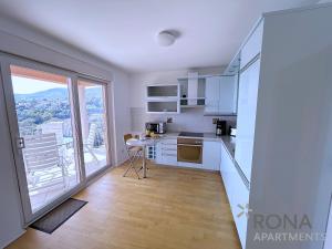 a kitchen with white cabinets and a large window at Rona Spacious apartment with a panoramic view in Ičići +16 photos