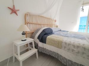 ein Schlafzimmer mit einem Bett und einem Tisch mit einer Lampe in der Unterkunft OasiMareBlu in Marina di Ragusa