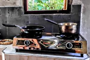 a stove with two pots and pans on it at Bee Line Holiday Apartment in Dickwella