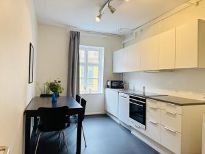 a kitchen with white cabinets and a black table and a tableablish at aday - 8 bedroom Apartment on the Pedestrian Street in Aalborg