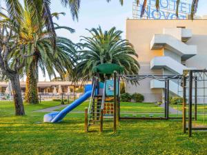 a playground with a slide in a park with palm trees at Novotel Porto Gaia in Vila Nova de Gaia
