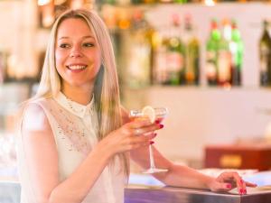 a woman is smiling while holding a glass of wine at Novotel Porto Gaia in Vila Nova de Gaia