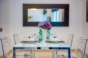a table with chairs and a vase of purple flowers at The Smart Concierge - Delphine in Dubai
