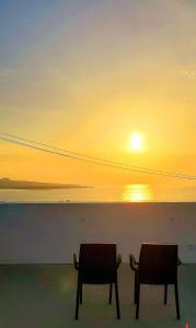 two chairs sitting in front of the ocean at sunset at Bagus in Nakijin