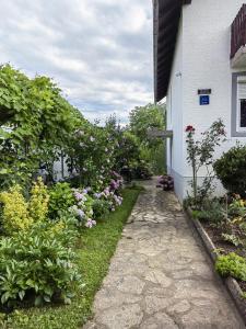 a garden path next to a white building with flowers at Apartman Barbara in Grabovac