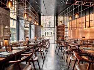 un ristorante con tavoli e sedie in legno e finestre di Radisson Blu Das Triest Hotel, Vienna a Vienna